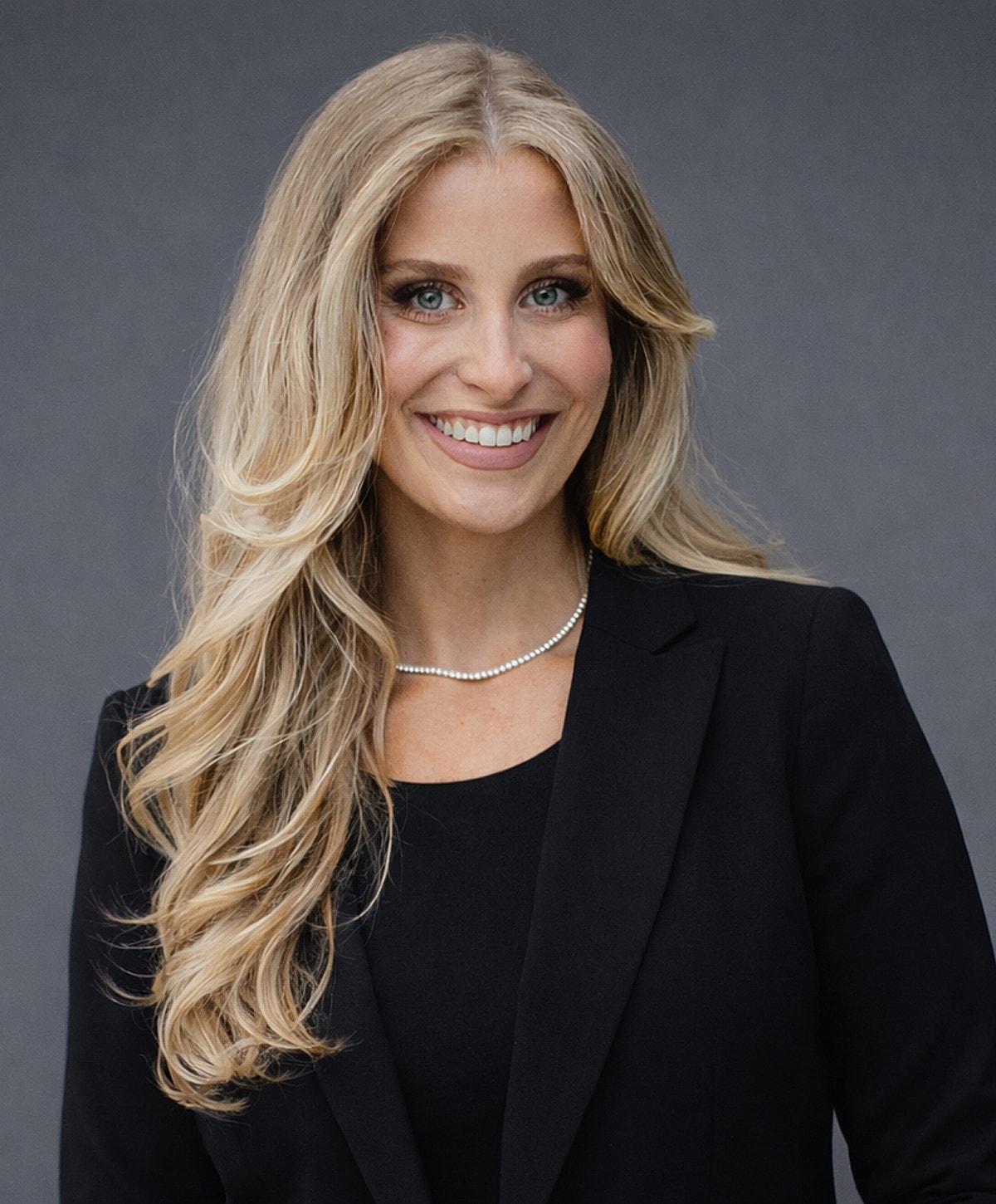 Professional woman smiling in black attire.