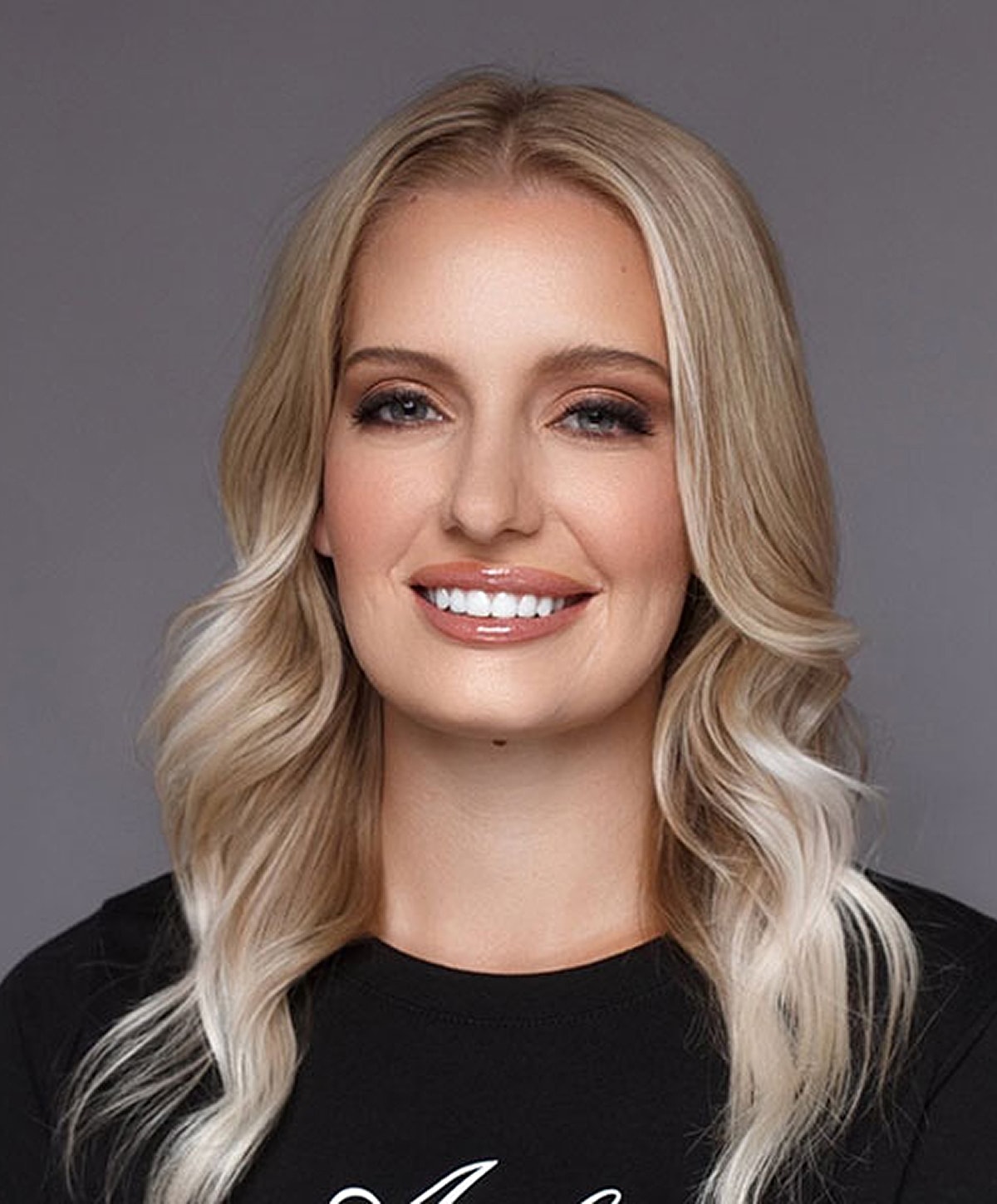 Smiling woman with blonde hair and subtle makeup.