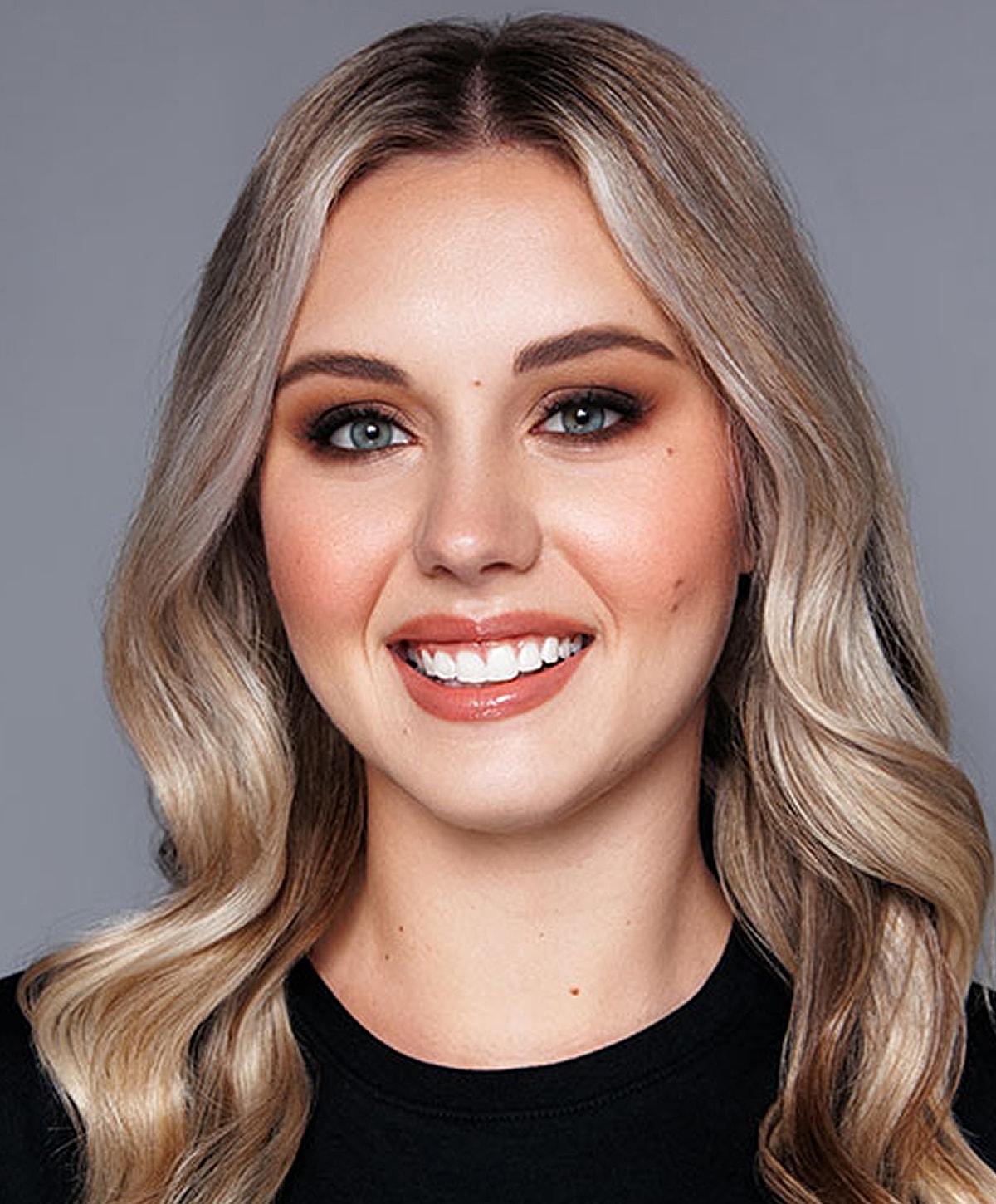 Smiling woman with blonde wavy hair.