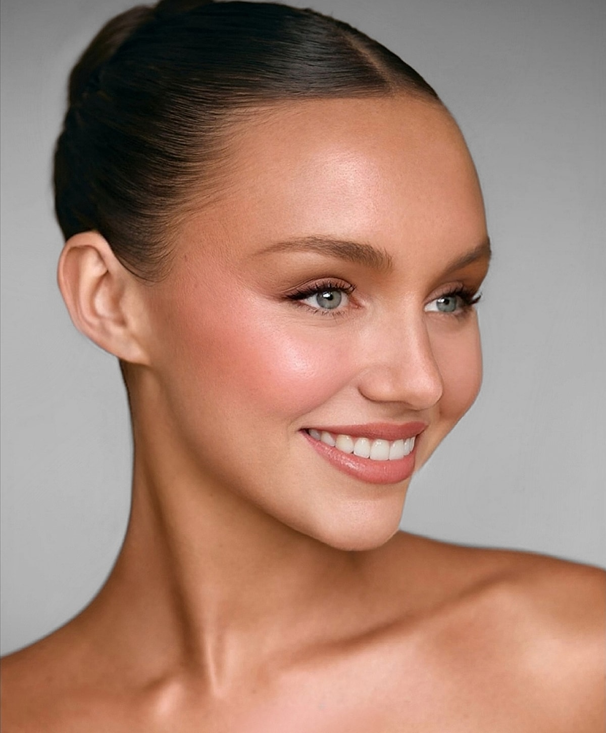 Smiling woman with smooth skin and elegant hairstyle.