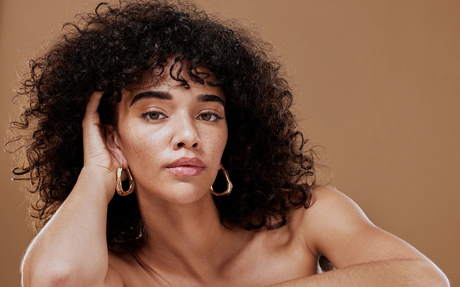 Person with curly hair and hoop earrings.