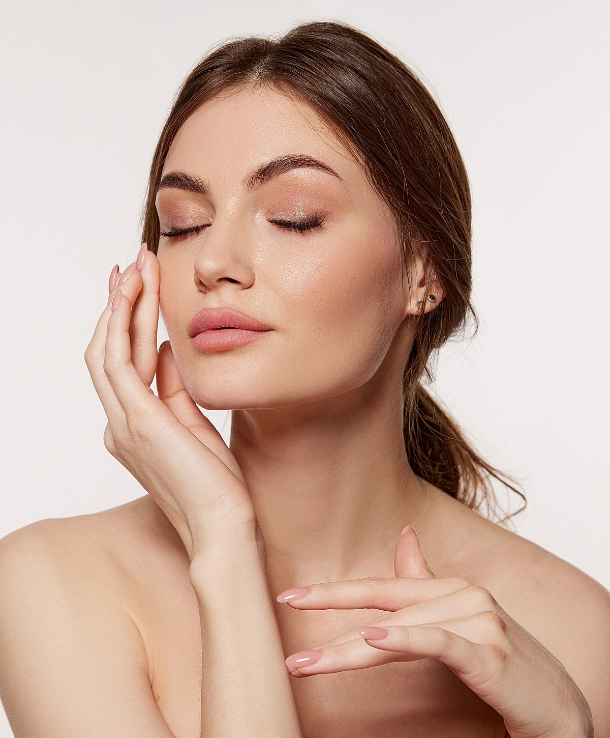 Woman with closed eyes touching her face.