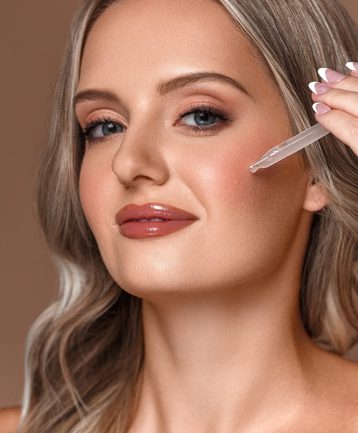 Woman applying serum to her face.