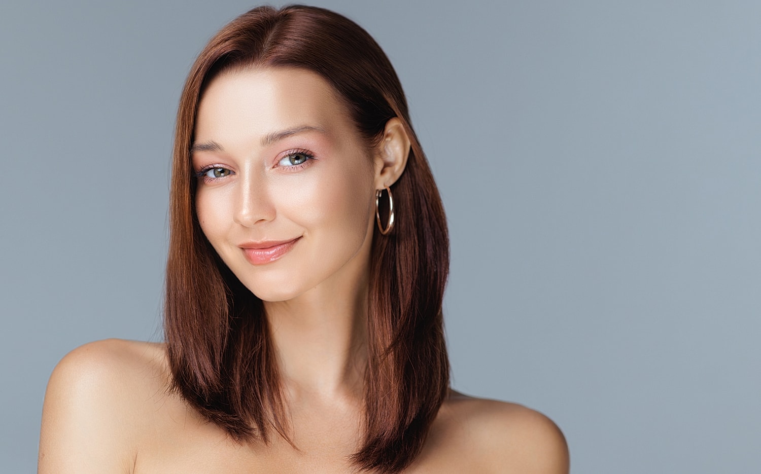 Woman smiling against a gray background.