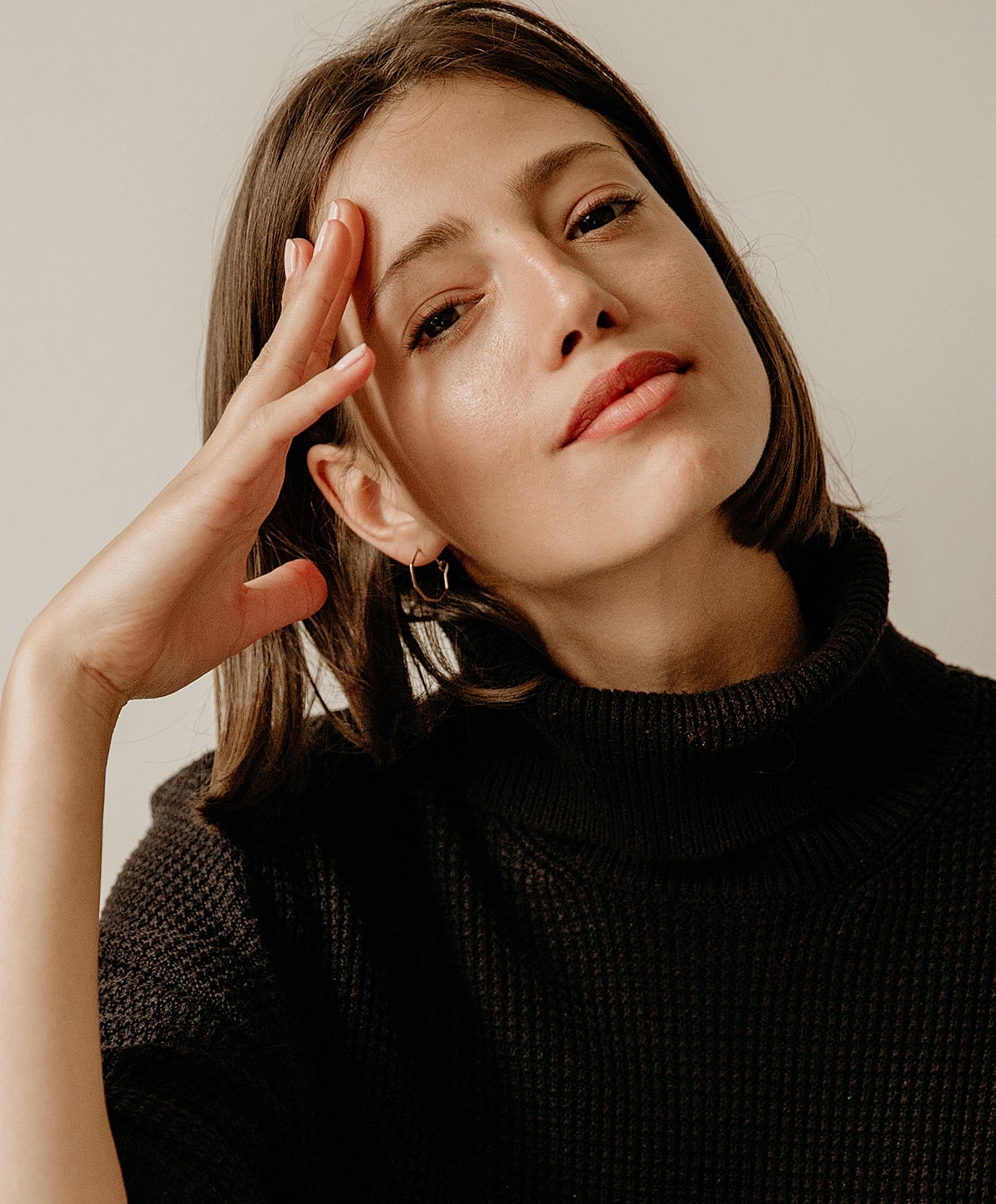 Woman in a black turtleneck, thoughtful expression.