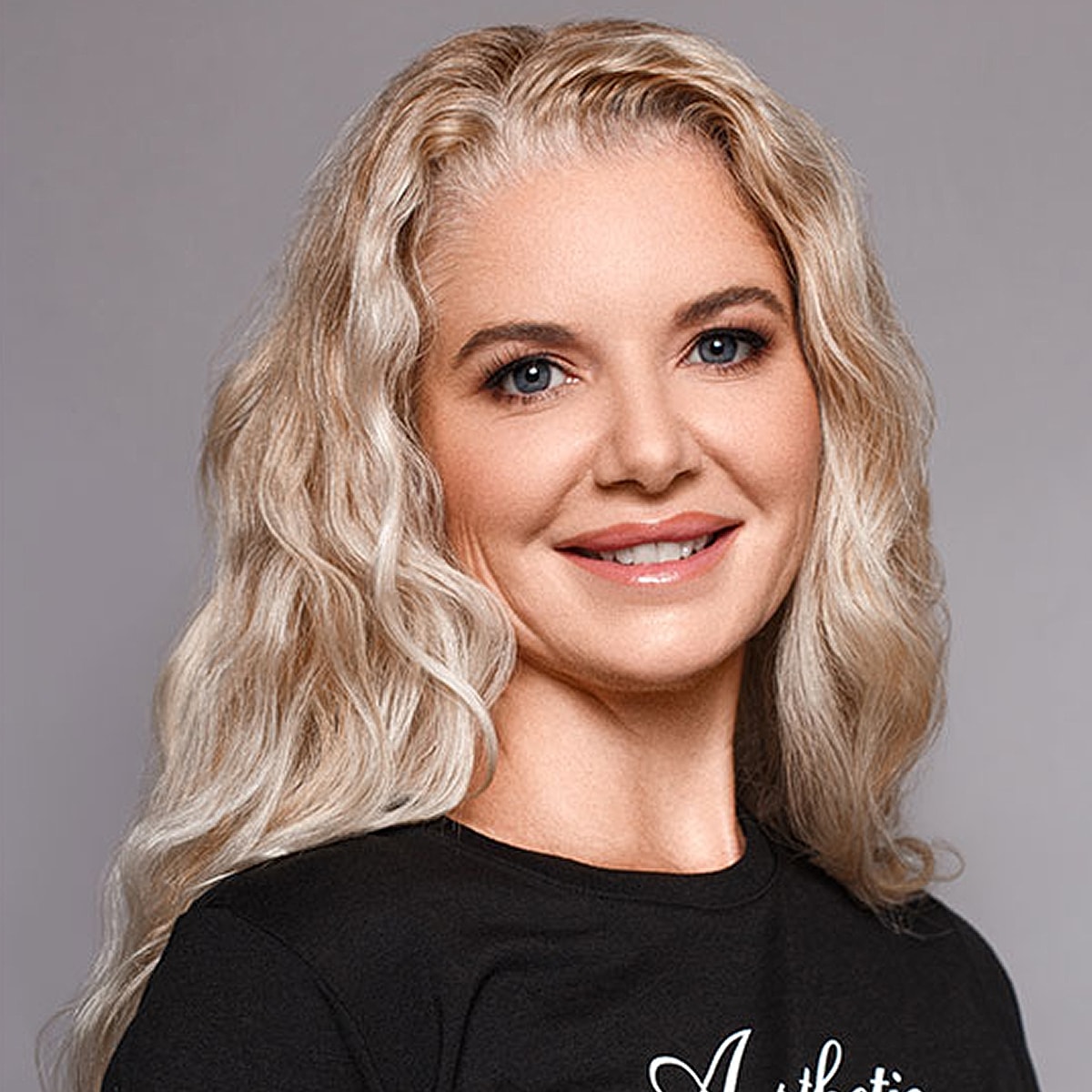 Smiling woman with long, wavy blonde hair.